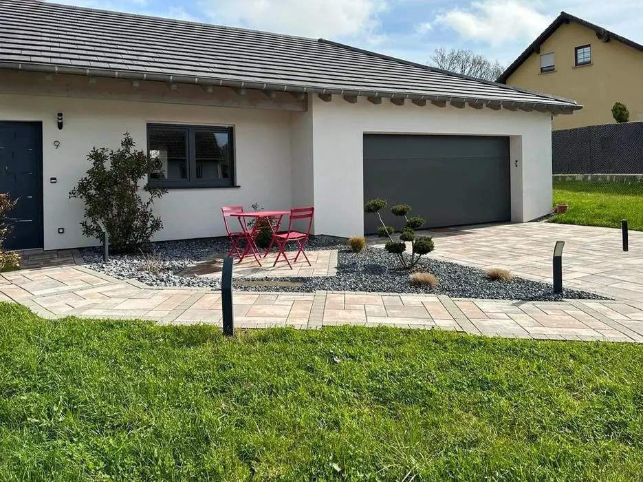 Aménagement extérieur résidentiel moderne avec terrasse dallée en pierre naturelle, jardins minéraux à graviers décoratifs gris, plantations d'arbustes et conifères en bacs