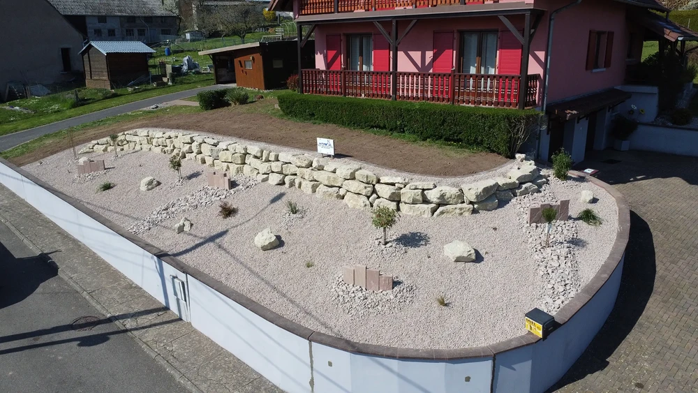 Chantier extérieur résidentiel avec allée d'accès fraîchement goudronnée menant à un garage