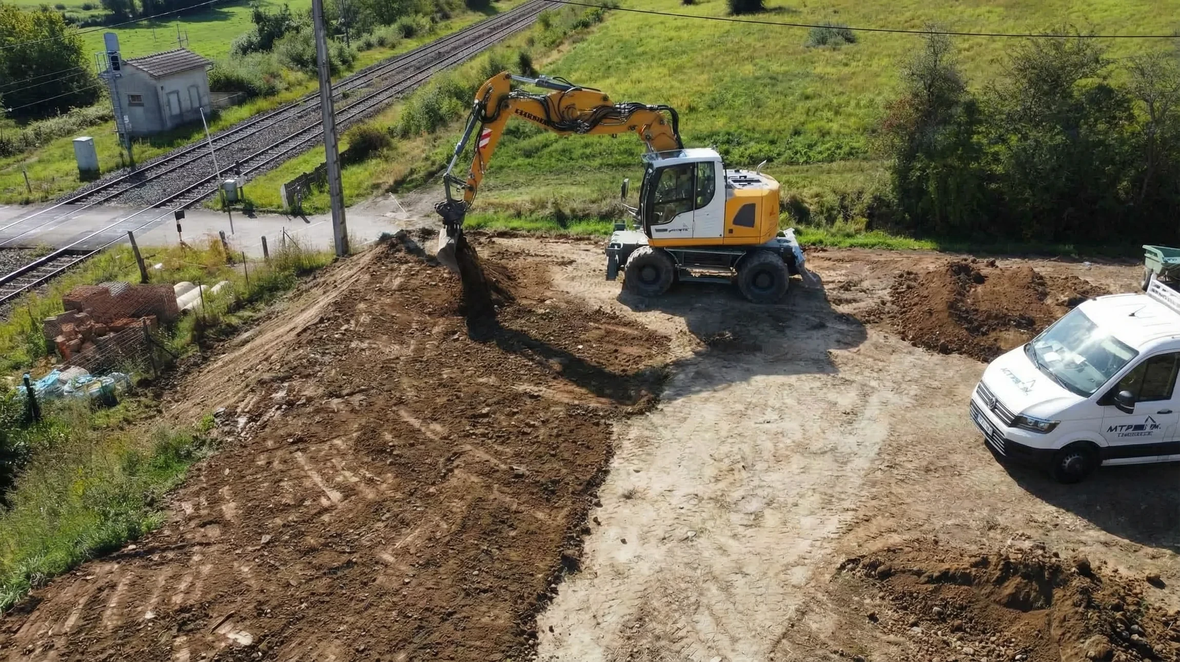 Chantier de terrassement en extérieur avec bulldozer jaune sur chenilles et pelleteuse hydraulique en arrière-plan